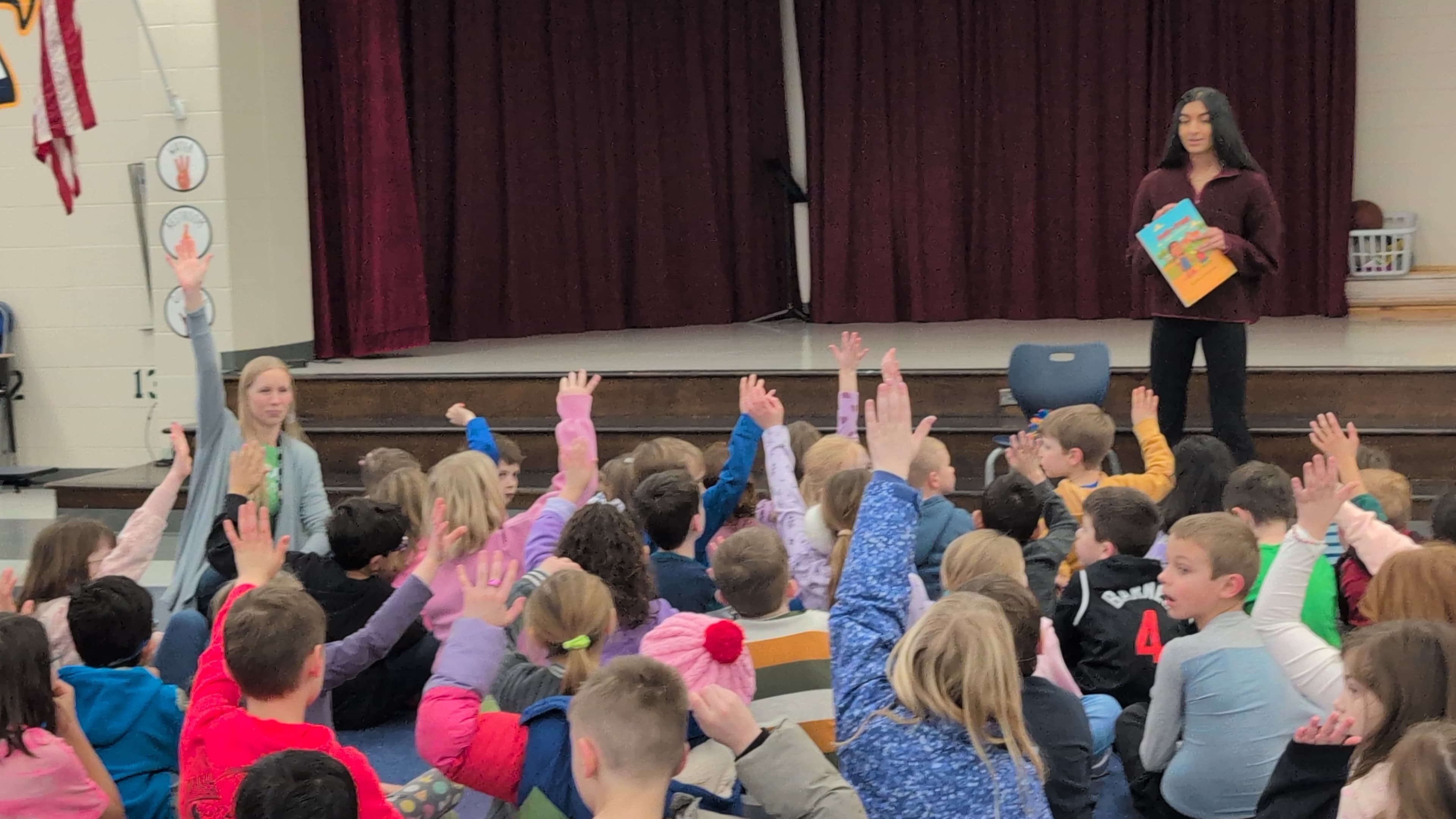 Students raising hands during book presentation